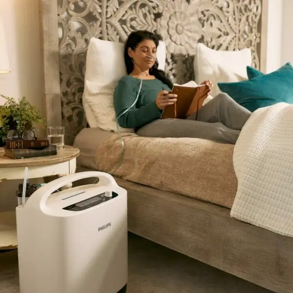 Mulher na cama a ler enquanto usa o kit de oxigénio Philips Oxygenate 5